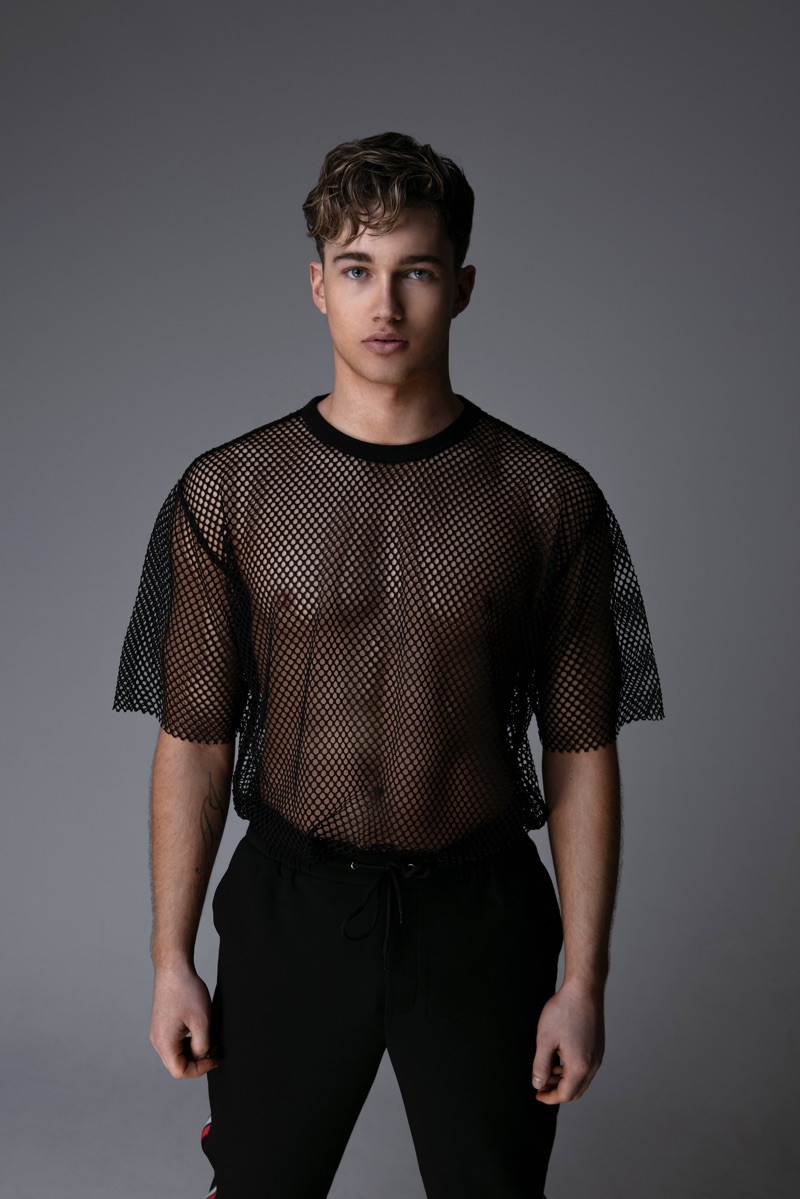 Connecting with Gay Times, AJ Pritchard rocks an oversized mesh tee.