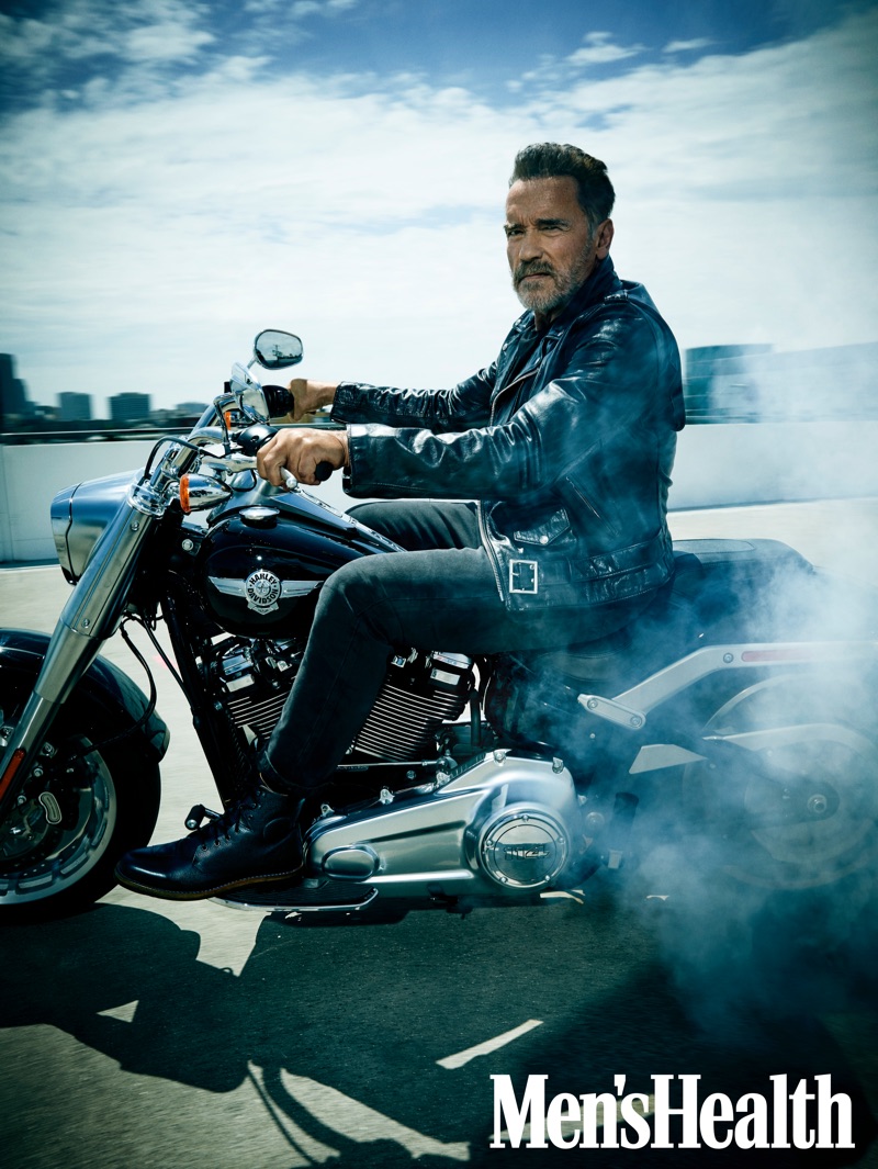 Arnold Schwarzenegger sports a Schott leather biker jacket with jeans and boots by Aether for Men's Health.