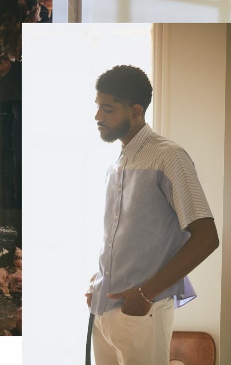 Elijah Fennell sports a striped Maison Margiela shirt, 5-pocket pants, a measuring tape belt, and open cuff bracelet.