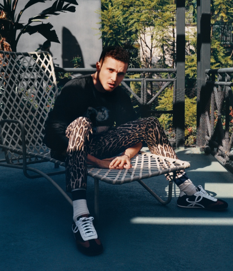 Embracing a streetwear vibe for his Mr Porter shoot, Karl Glusman sports a Rhude t-shirt, Dries Van Noten leopard-print trousers, and Loewe sneakers.