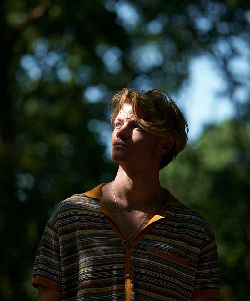 Connecting with Mr Porter, Tom Rhys Harries dons a Le Gramme necklace with a camp-collar striped knit shirt by Nanushka.