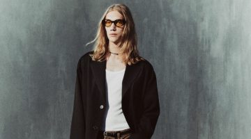 Valentyn Boiko wears a wool coat with waxed effect jeans, square toe leather Chelsea boots, and oval sunglasses from the Zara Edition pre-fall 2023 collection.