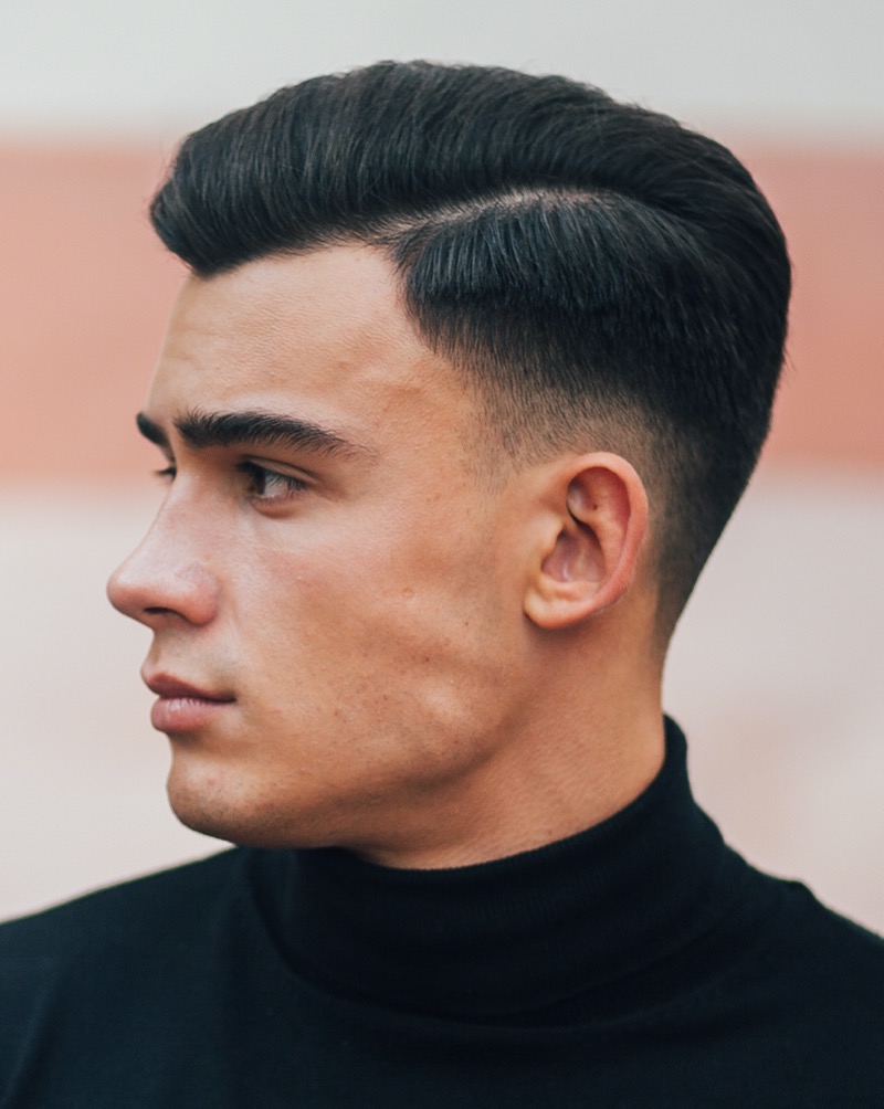 The fade adds a modern update to the side part hairstyle.